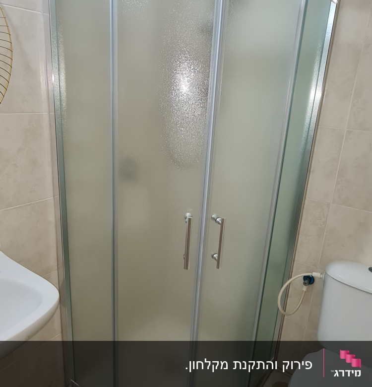 מקלחון זכוכית עם דלתות מתכת בחדר אמבטיה